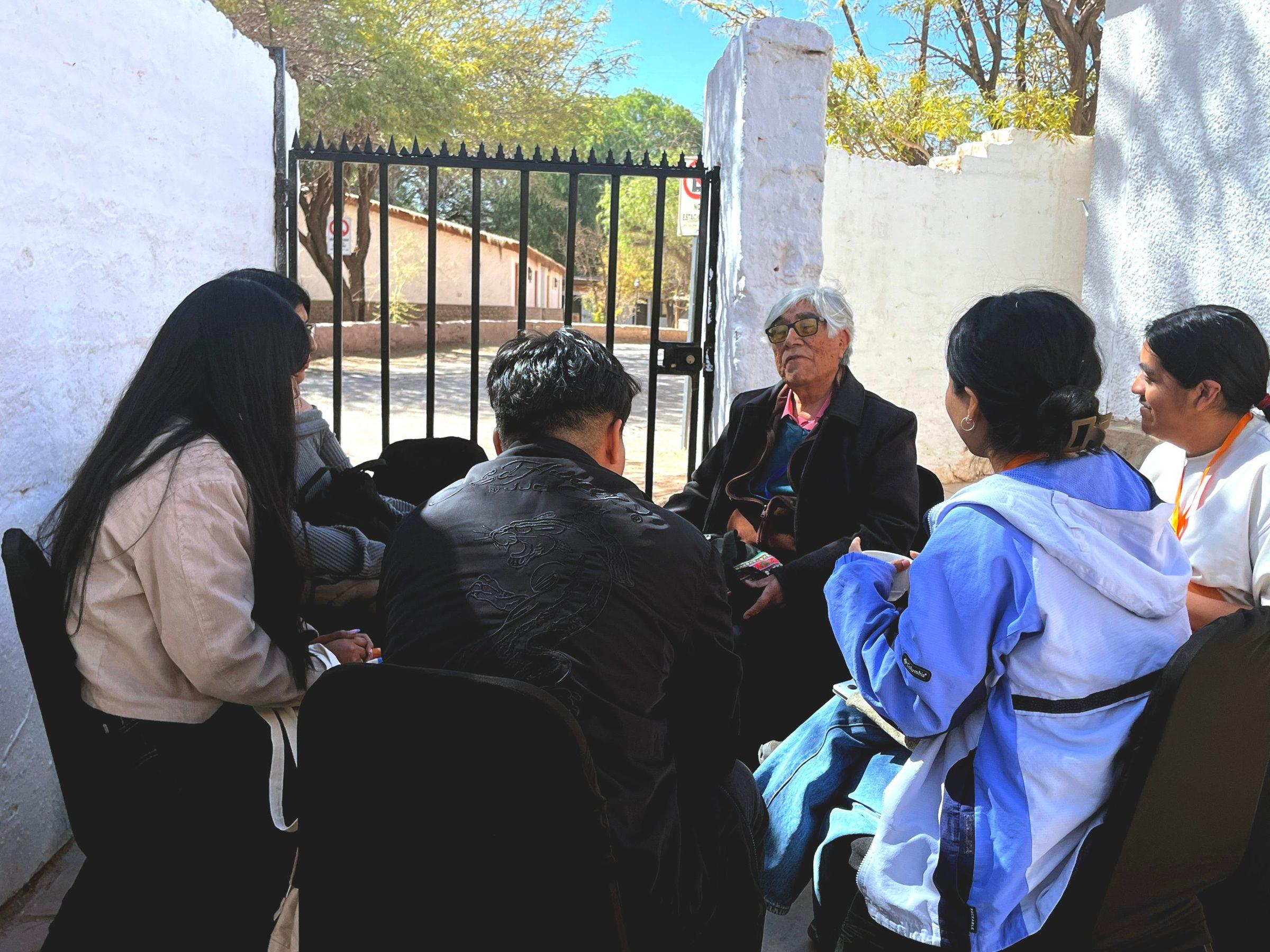 Participantes conversan en círculo con un invitado al aire libre