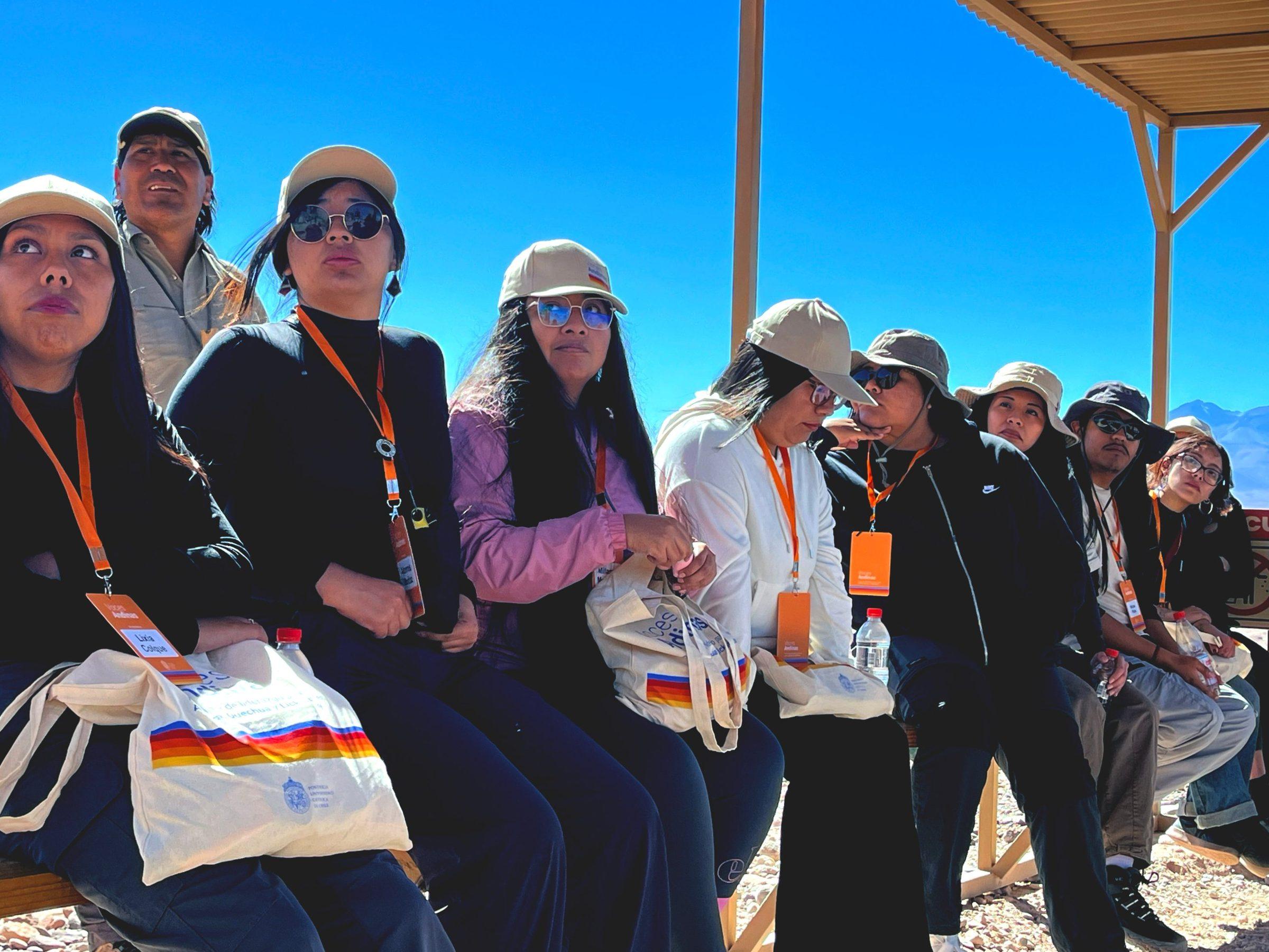 Participantes con gorros y credenciales conversan sentados durante una salida a terreno
